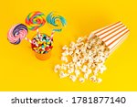 a top view colored lollipops with candies inside basket along with popcorn on the yellow background rainbow sweet sugar