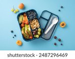 Top view of a colorful and balanced school lunch with fresh fruits, vegetables, sandwich, and nuts in a blue lunch box