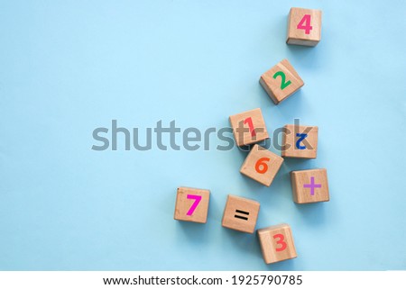 Top view of colorful bricks on turquoise wooden table background. Figures and arithmetic signs. Education concept