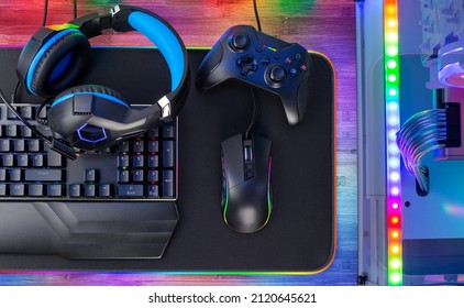 Top View Of A Colorful Bright Pc Rgb LED Gaming Desk With Headset Keyboard Mouse And Desktop Computer.  Esports Technology Concept Background