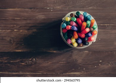 Top view, colorful felt pens on dark wooden table. Toned photo, shallow depth of field.