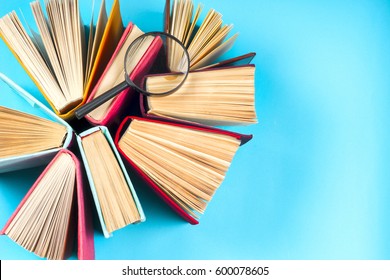 Top view of colorful hardback books in a circle and magnifying glass. free copy space. Back to school copy space. Education background.