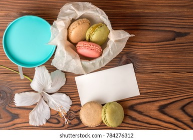 Top View Of Colorful Macarons Cake In Gift Box, Empty Blank,  And Hibiscus Flower On Wooden Background, Copy Space