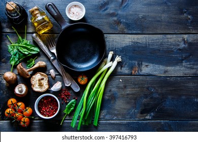 Top view of colorful organic vegetables and seasoning ingredients on rustic kitchen table with olive oil and balsamic vinegar. Healthy food or vegetarian food concept.