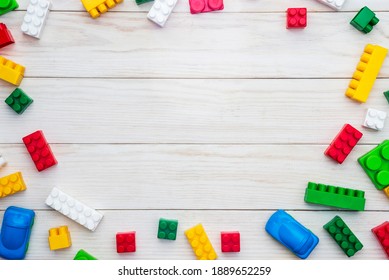 Top View Of Colorful Plastic Toy Bricks On A White Wooden Background. Baby Kids Toys Background.