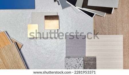 top view combination of interior material board samples contains travertine tile, gold stainless, roller blind drapery swatch, wooden vinyl flooring tile, interior fabric wallpaper, quartz, laminated.