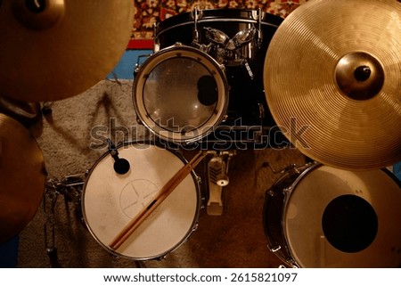Top view of complete drum set with worn out drumsticks placed on drumhead in recording studio, copy space
