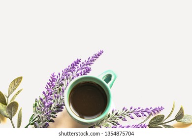 Top view composition of turquoise cup of coffee with purple lavender flowers and green leafs on white background Spring concept with copy space. Flat lay.