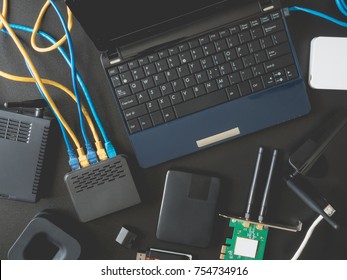 top view of Computer Network Devices concept with Hub, Computer Laptop, Switch, Router, Modem, wireless card, lan cable, USB wifi adapter on black table background