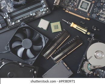 Top View Of Computer Parts With Harddisk, Ram, CPU, Graphics Card, Solid State Drive (SSD), Motherboard, Tools And Fan Case On Black Steel Background.