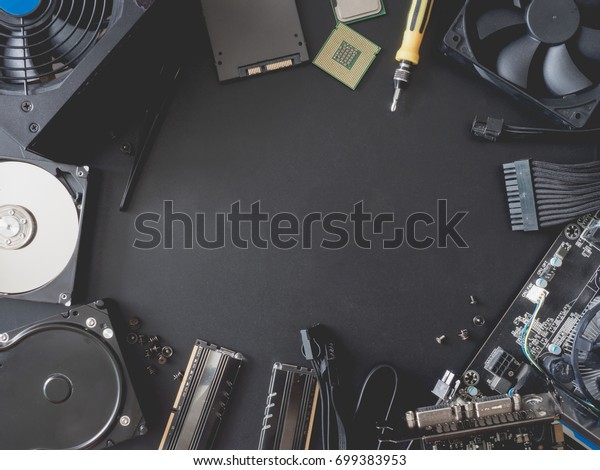 top view of computer\
parts with harddisk, ram, CPU, graphics card, solid state drive\
SSD, motherboard, tools, PSU Power Supply and Fan case on black\
steel background.