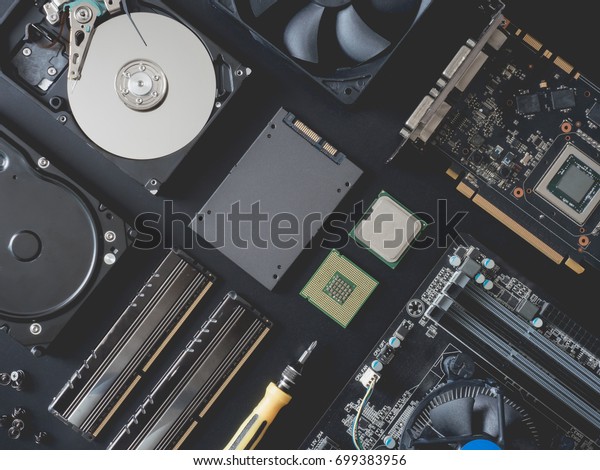 top view of computer parts with harddisk,\
ram, CPU, graphics card, solid state drive (SSD), motherboard,\
tools on black steel\
background.
