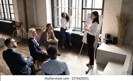 Top view concentrated different generations mixed race employees listening to skilled speaker, presenting new project or marketing strategy during educational workshop seminar at modern loft office. - Shutterstock ID 1575620551