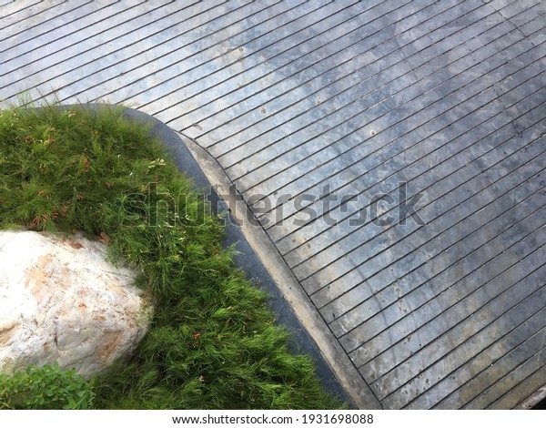 top view of concrete ramp with groove line and small\
garden with big rock