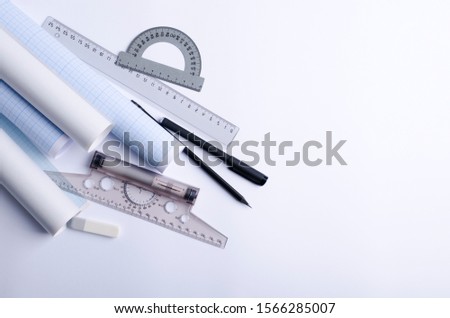 Top view of constructor professional tools on the white blank paper.Protractor, pencils, t-square, ruler, graph paper on the white surface, empty space for text