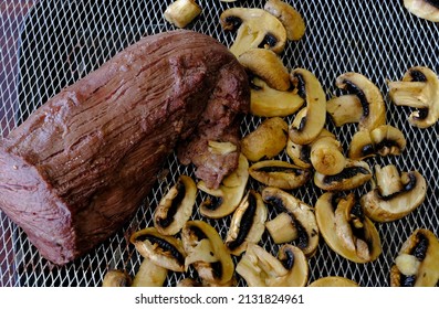 Top View Of Cooked Beef Tenderloin Roast With Golden Sliced Mushrooms In Air Fryer Basket