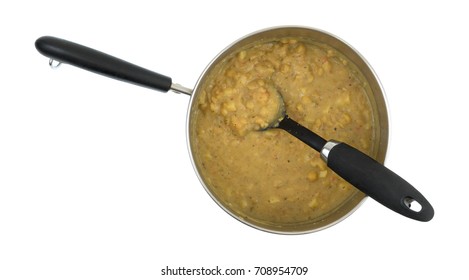 Top View Of Cooked Leftover Yellow Split Pea Soup With Vegetables In A Metal Pan With A Spoon In The Food Isolated On A White Background.