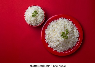 Top View Of Cooked Plain White Basmati Rice In Red Bowl And Plate On Red Background