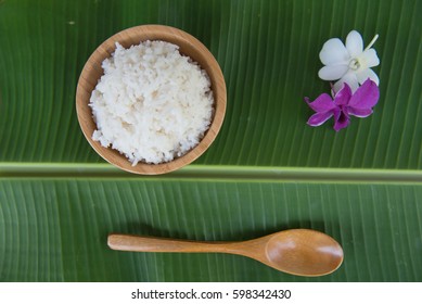 Top View Cooked Rice In Bowl On Green Banana Leaf Spoon And Orchid .