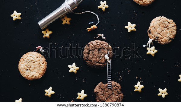 Top view cookies with miniature
people astronaut and painting group working in galaxy.
