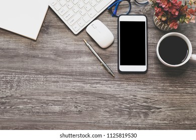 Top view with copy space and flat lay of the business office table with keyboard, mouse glasses, pen ,smartphone for mock up and coffee cup on wooden desk background - Shutterstock ID 1125819530
