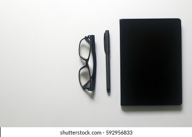 Top view with copy space, flat lay.White office desk table with notebook,pen and glasses.