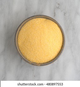 Top view of corn meal in an old bowl atop a gray marble cutting board. - Shutterstock ID 480897553