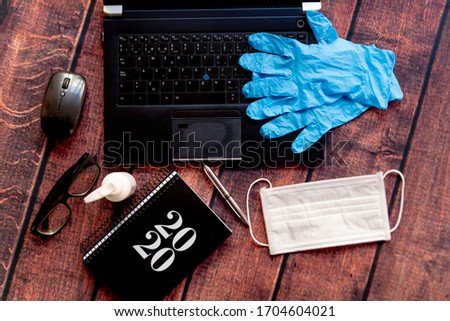 top view of coronavirus remote work kit on wooden office desk with hand sanitizer and face mask, a solution against the spread of covid19 for employees