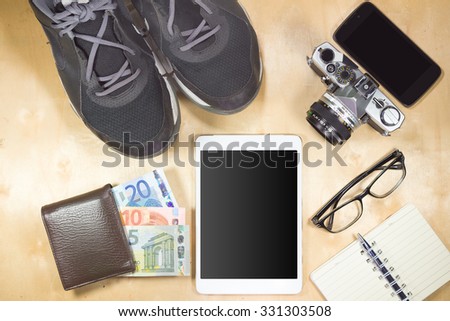 Top view of Costumes of the travelers - Sneaker, smart phone, tablet, camera, notebook, wallet on the wooden floor vintage style.