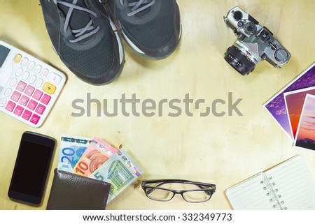 Top view of Costumes of the travelers - Sneaker, smart phone, tablet, camera, notebook, wallet, calculator, glasses on the wooden floor vintage style.  ( Composition and space for text )