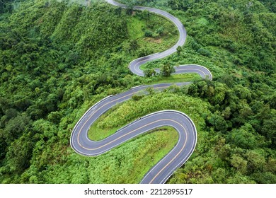 Top View Of Countryside Road Passing Through The Green Forrest And Mountain