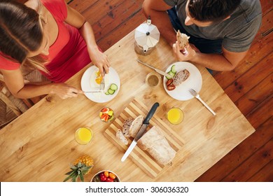 Top View Of Couple Enjoying A Healthy Morning Breakfast In Kitchen At Home. Breakfast Table With Loaf Of Bread, Fruits, Juice And Coffee.