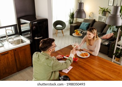 Top View Of Couple Having Lunch At Home. Young Smiling Couple Eating Pasta And Toasting With Wine.