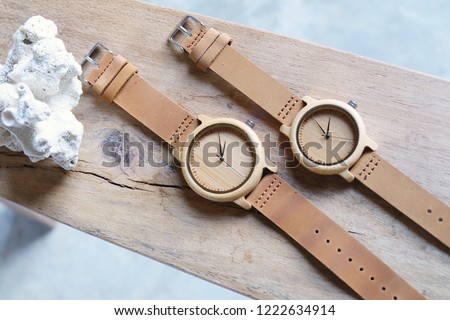 Top view of craft wooden couple watches and brown leather band on wood and white coral. Hand watch products for woman and man. 