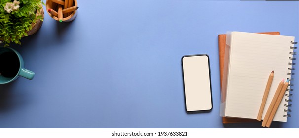 Top view of creative flat lay workspace with smartphone, stationery, cup, plant pot and copy space, clipping path