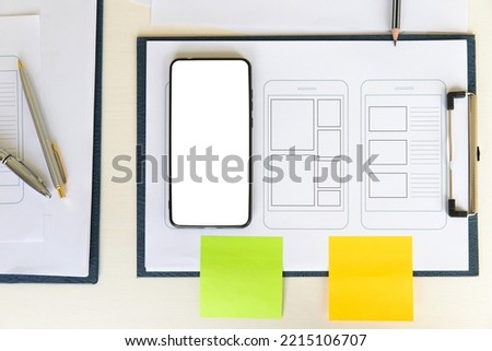 Top view of Creative flat lay UX designer working space and office supplies. Smartphone application layout prototype project.