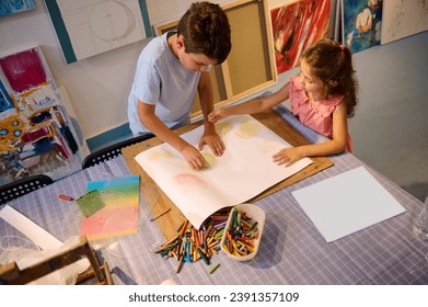 Top view of creative kids during an art class in a daycare center or elementary school classroom drawing with female teacher. People. Entertainment for children. Fine and visual art concept. Leisure - Powered by Shutterstock