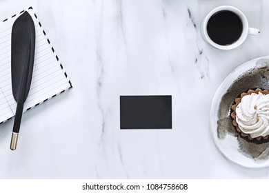 The Top View Of Creative Marble Desk With Cup Of Coffee, Cake And Notes. Concept For Mock Up Clack Bussines Card.