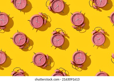Top view of creative pattern made of pink alarm clocks on a yellow background, flat lay. Wake-up and good morning concept. Punctuality. Countdown and deadline. Sleeping time. Business planning. Top vi