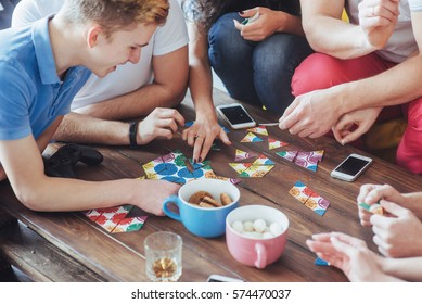Top view creative photo of friends sitting at wooden table. Friends having fun while playing board game