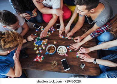 Top view creative photo of friends sitting at wooden table. Friends having fun while playing board game.