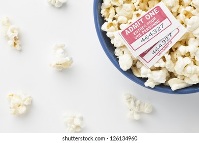 Top View And Cropped Image Of A Pop Corn Bowl With Movie Tickets Above And Scattered Pieces On A White Background