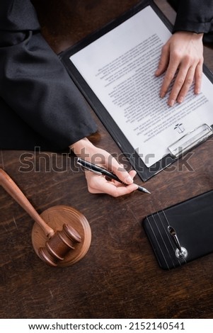 top view of cropped prosecutor with pen near lawsuit and gavel