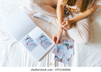Top view of Cropped woman hands holding and watching a family photo album. Mother sit on bed and watching album with little baby son kid boy.