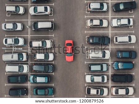 Top view of the crowded Parking lot with quadcopter or drone. Original bright automobile among the grey of mediocre cars. Parking space search, No parking space.