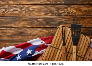 top view of crumpled american flag and bbq equipment on wooden rustic table with copy space