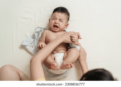 Top view crying Asian baby wearing clothes by his mother. Concept babies healthcare. - Powered by Shutterstock