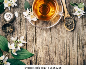 Top View Of Cup Of Asian Hot Green Tea And Jasmine Flower On Rustic Wooden Table With Copyspace. Herbal And Alternative Medicine Background.