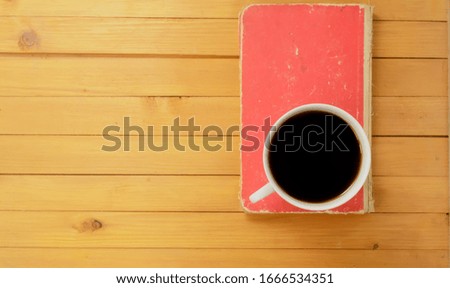 Top view, A cup of coffee and closed red book on wooden background