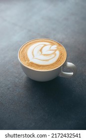 Top View Of A Cup Of Coffee With Latte Art Tulip On A Dark Moody Background. Home Barista And Delicious Capuccino Concept